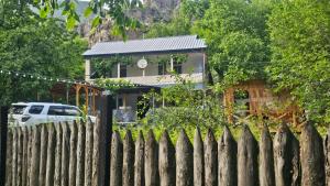 a house behind a fence with a car parked in front at Vardzia Old Village in Vardzia