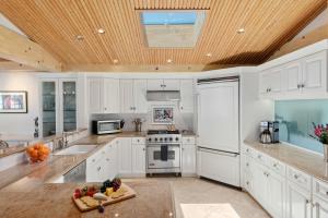 a kitchen with white cabinets and a wooden ceiling at Padaro Sands in Carpinteria