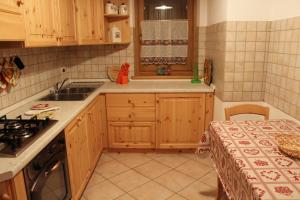 a small kitchen with wooden cabinets and a sink at Casa Monego in Fusine