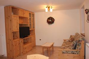 a living room with a tv and a couch and a chair at Casa Monego in Fusine