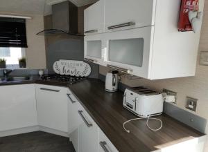 a kitchen with white cabinets and a counter top at Craig Tara Beach Lodge in Ayr +4 photos