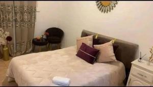 a bedroom with a white bed with pillows and a chair at Appartement F3 équipé lux in Skikda