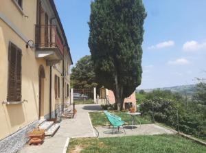 a yard with a tree and a bench and a building at Mulimù - Guesthouse in Montecalvo Versiggia