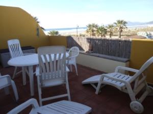un balcón con sillas blancas, mesa y sillas en Livingtarifa La Tortuguita en Tarifa