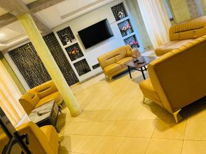 a living room with yellow chairs and a flat screen tv at Spark Africa Hotel in Jinja