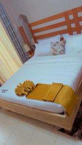 a large bed with white sheets and a wooden headboard at Spark Africa Hotel in Jinja