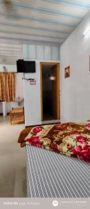 a bedroom with a bed and a tv on the wall at S K S HOME STAYs in Vālpārai