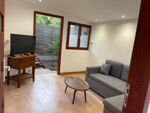 a living room with a couch and a table and a tv at Le Petit Pêcheur in Étang-Salé