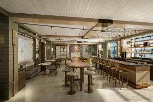 a restaurant with a bar and tables and chairs at The Harborvale, Autograph Collection in Burlington