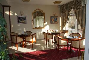 a dining room with tables and chairs and a mirror at Hotel Vila Ariston in Osijek