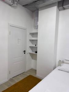 a white bedroom with a bed and a white door at Хостел in Astana