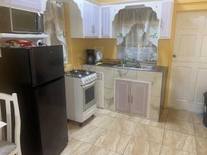 a kitchen with white cabinets and a black refrigerator at Country Green in La Feuillet