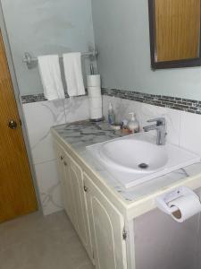a white bathroom with a sink and towels at Country Green in La Feuillet