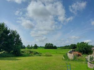 a field of grass with a blue sky and clouds at Sonnenterrasse in Hörup