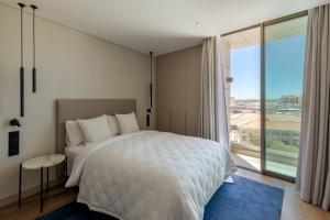 a bedroom with a white bed and a large window at The Downtown Largo do Carmo in Faro