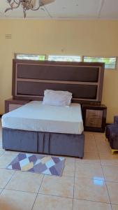 a bedroom with a bed with a large headboard at Quantico Guest house villa in Ndola