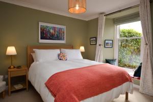 a bedroom with a bed with a red blanket and a window at Lochview at 33a in Gourock
