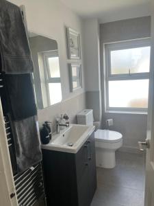 a bathroom with a sink and a toilet and a mirror at Coastal Charm Seaside House in Moelfre +46 photos