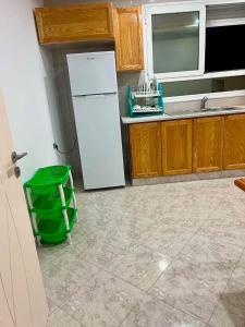 a kitchen with a white refrigerator and a green trash can at Dar Meriem in Korba