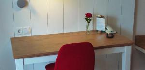 a desk with a red chair and a vase with a rose at Pescheks Tagungshaus Walsrode in Walsrode