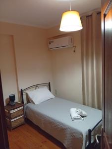 a bedroom with a bed with a white blanket and a lamp at Amentas Luxury Apartments in Vrontádos