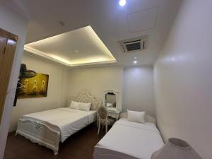 a bedroom with two beds and a table and a ceiling at Hanoi Better Hotel & spa in Hanoi