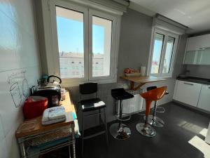 a kitchen with two windows and a counter with stools at Atico en el centro de Vitoria Parking gratis in Vitoria-Gasteiz