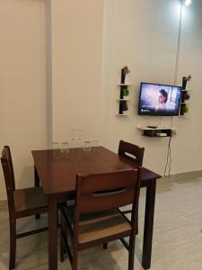 a dining room table with chairs and a television at PINES and PETALS in Jorhat
