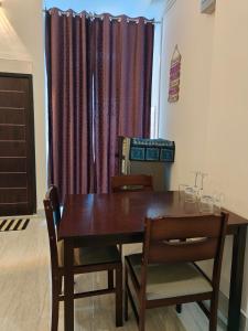 a dining room table and chairs with purple curtains at PINES and PETALS in Jorhat