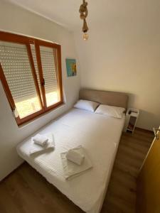 a small bedroom with a white bed with a window at Vikendica sa bazenom in Višegrad +45 photos