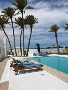 a swimming pool with chaise lounges and palm trees at maison rachid in El Guecheïne +20 photos