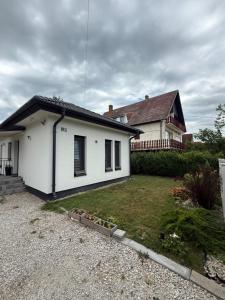 a white house with a yard in front of it at Sunset Villa Balatonfenyves in Balatonfenyves