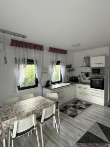 a white kitchen with a table and chairs in it at Sunset Villa Balatonfenyves in Balatonfenyves