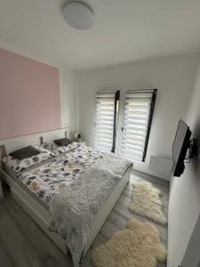 a bedroom with a bed and two windows and two rugs at Sunset Villa Balatonfenyves in Balatonfenyves