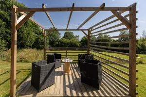 a wooden pergola with chairs and a table on a deck at Le Container de Jeff - Maison bois, grand jardin in Uzel