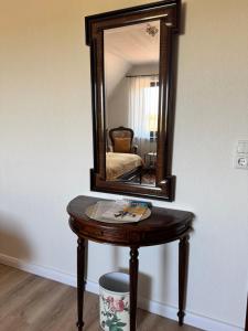 a wooden table with a mirror on a wall at Ferienwohnung Klahn Neue Tiefe in Neue Tiefe Fehmarn
