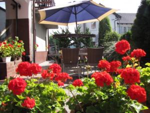 a patio with red flowers and an umbrella at Jagienka in Łeba