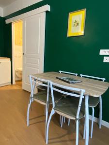 a table and chairs in a room with a green wall at Studio cosy - inspiré de Capri in Bar-le-Duc