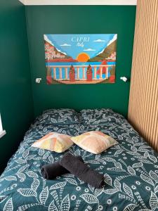 a bed with two pillows and a poster on the wall at Studio cosy - inspiré de Capri in Bar-le-Duc