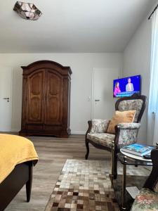 a living room with a wooden cabinet and a chair at Ferienwohnung Klahn Neue Tiefe in Neue Tiefe Fehmarn