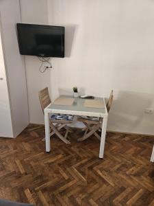 a white table with chairs and a tv on a wall at Sonček 2 in Izola