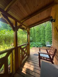 a wooden porch with a bench and a table at Cottage with access to the lake in Tarnów Jezierny
