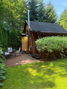 a wooden cabin with a patio and a table at Cottage with access to the lake in Tarnów Jezierny +8 photos