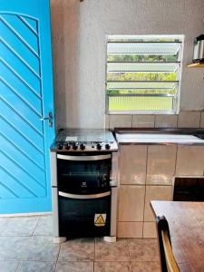 a kitchen with a stove and a blue door at Vila de Casas de Campo Rústica e Aconchegante na Mata Atlântica in Juquitiba