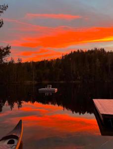 a boat sitting on a lake with a sunset at opplevelses hytta badestamp ridning osv in Skien