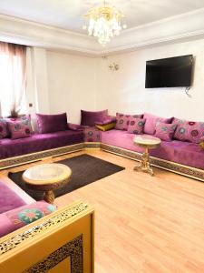 a living room with purple couches and a tv at super appartement centre avec parking in Tangier