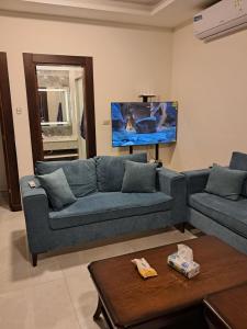 a living room with a blue couch and a tv at Muzn al Ghaith Luxury Chalet with Private Pool in Ash Shāghūr