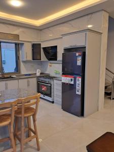 a kitchen with a black refrigerator and a table at Muzn al Ghaith Luxury Chalet with Private Pool in Ash Shāghūr