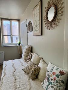 a bedroom with a bed with a mirror and pillows at Le Cocon Bohème, appartement chaleureux in Sarrebourg
