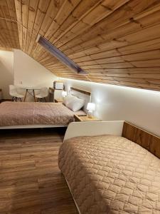 a bedroom with two beds and a wooden ceiling at Lukas Hotel in Muravitsa